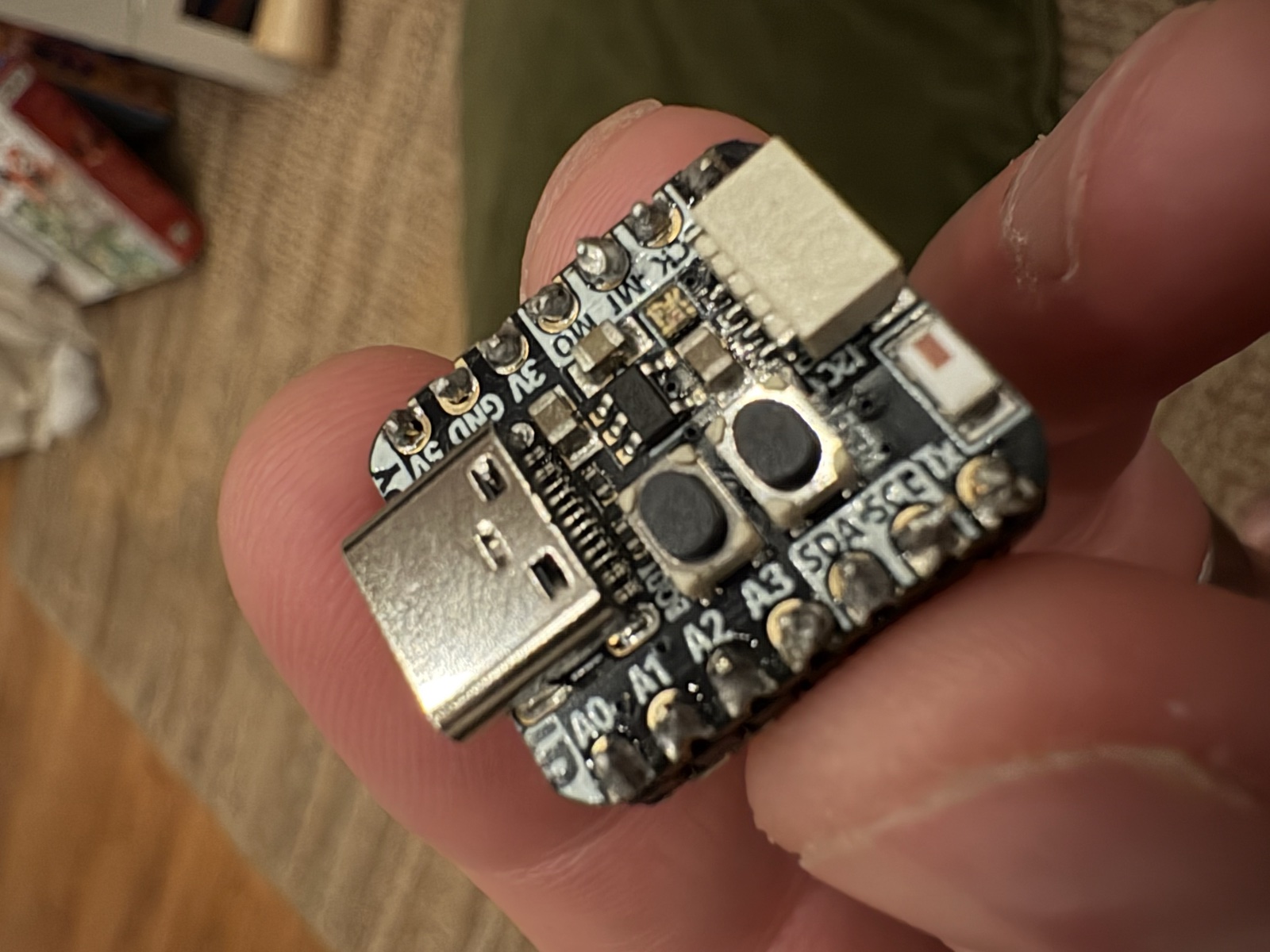 Adafruit QT Py ESP32-S3 microcontroller held in fingertips showing tiny micro scale